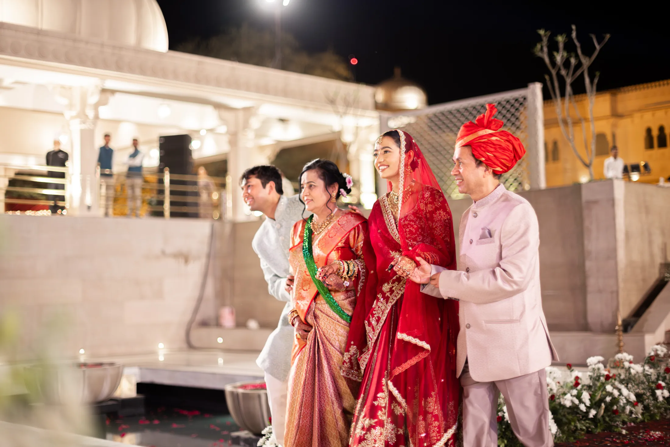Serene smiles in a red bridal outfit while walking with family