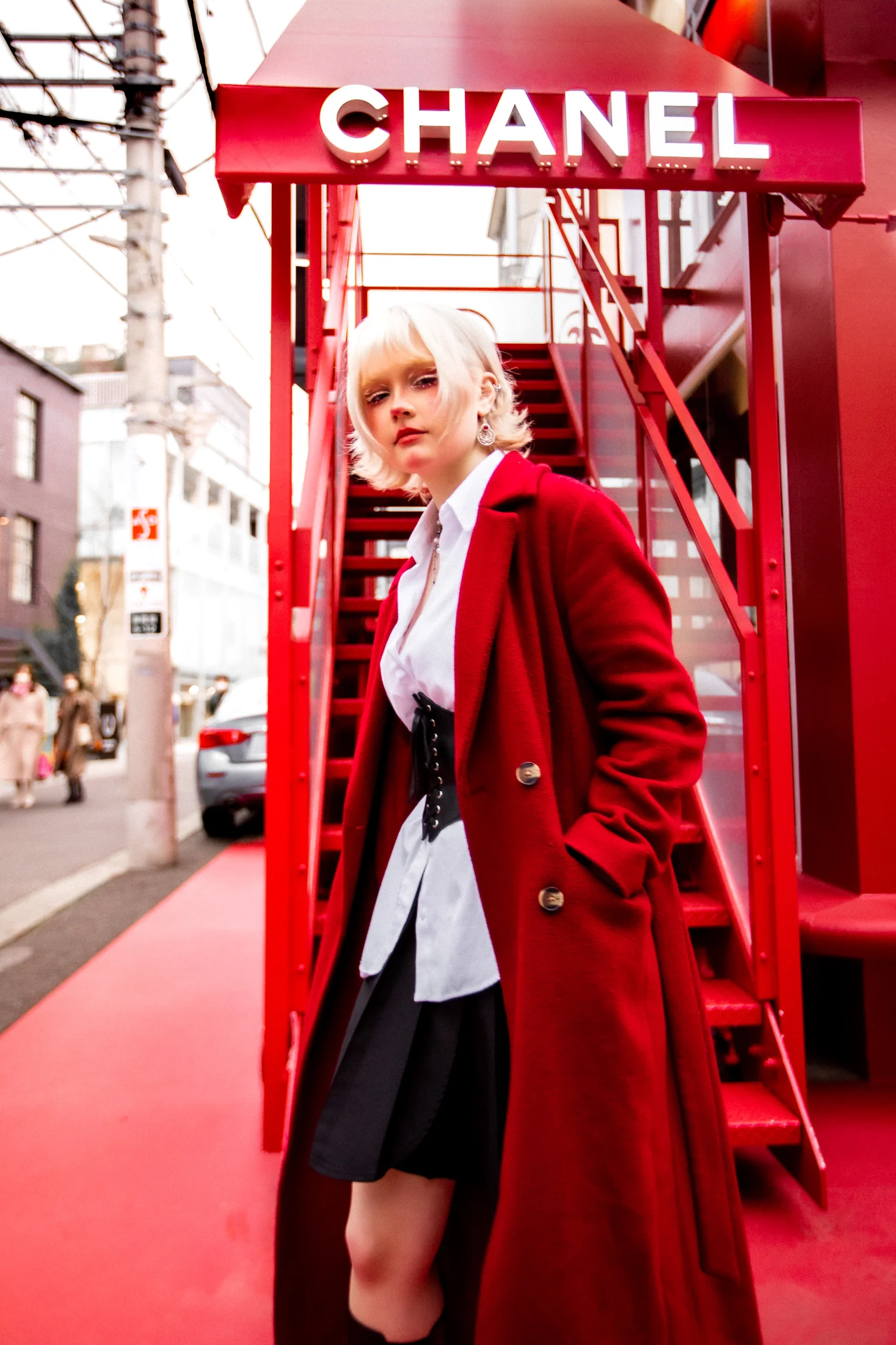 Ylva Brandt in a red coat beneath a Chanel storefront sign